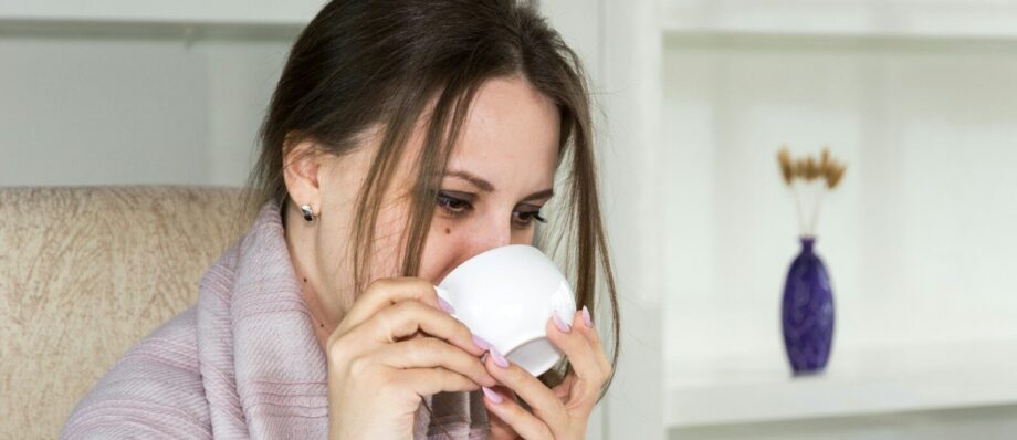 a woman sitting in a chair drinking from a cup
